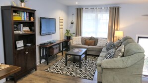 A living room with a sofa, coffee table, bookshelf, and a TV. - Wonderful 3BDR Guest Suite Sits Between Downtown and the Beach (Charleston)