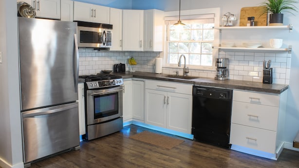 A modern kitchen with stainless steel appliances, white cabinets, and a wooden floor. - Wonderful 3BDR Guest Suite Sits Between Downtown and the Beach (Charleston)