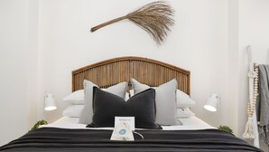 A neatly made bed with a black and white bedspread, a wooden headboard, and a 'Welcome' sign. - Oceanview Kiama Luxury Coastal Accommodation (Kiama)