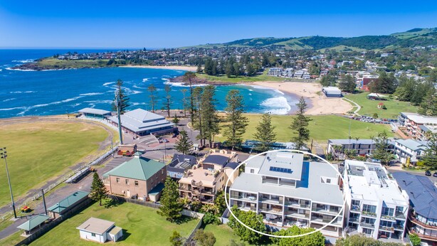 An aerial view of a coastal town with a beach, a large building with multiple floors, and surrounding greenery. - Oceanview Kiama Luxury Coastal Accommodation (Kiama)