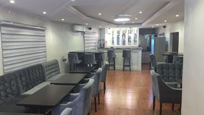 A restaurant with a long counter, cushioned seating, and a bar area. - RM Suites (Lagos)