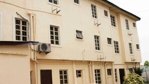A multi-story building with a beige facade, multiple windows, and a small air conditioning unit mounted on the exterior wall. - RM Suites (Lagos)