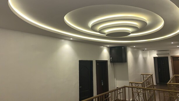 A modern interior with a circular ceiling design and a staircase with ornate railings. - RM Suites (Lagos)