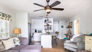 Un salon moderne avec un canapé, un pouf et un ventilateur de plafond.