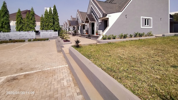 A residential area with modern houses, a paved driveway, and a grassy lawn. - Beckett Suites (Abuja)