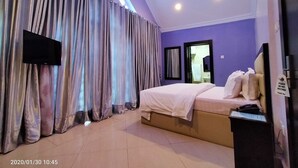 A hotel room with a bed, a television, a mirror, and a sign on the door. - Beckett Suites (Abuja)
