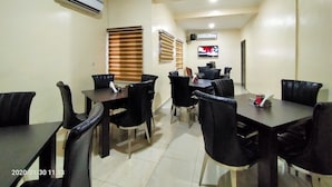 A conference room with a large table and chairs, air conditioning units, a television, and a window with blinds. - Beckett Suites (Abuja)