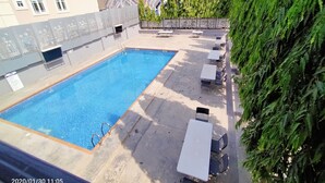 A rooftop swimming pool with a clear blue water surface, surrounded by lounge chairs and tables. - Beckett Suites (Abuja)