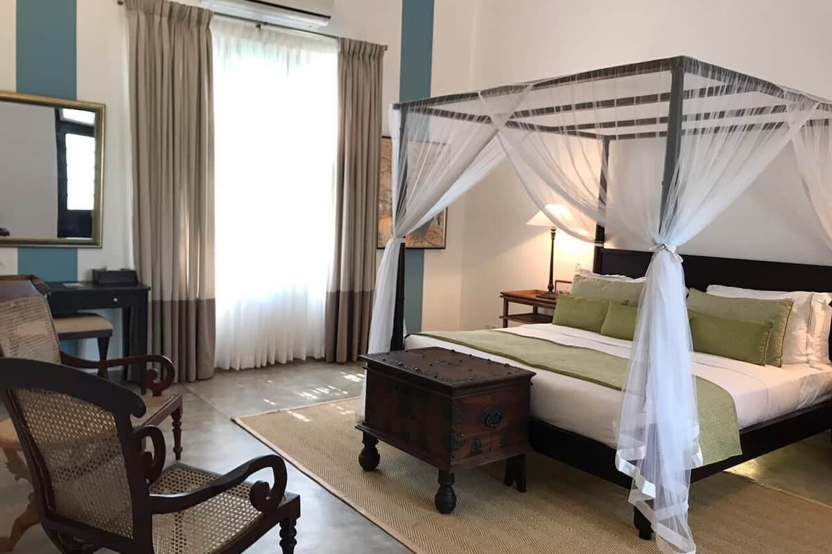 Un dormitorio con una cama con dosel, una mesita de noche de madera, una silla y un escritorio.