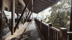 A covered balcony with a view of the sea, wooden railings, and a staircase leading to an upper level. - The Postcard Galle (Galle)