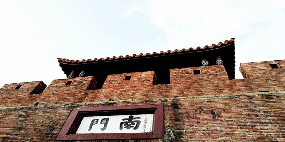 Un muro de ladrillo con un tejado tradicional de baldosas y un letrero con caracteres chinos.