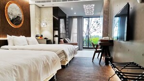 A hotel room with two beds, a desk, a chair, a TV, and a large window with a view of greenery. - Gala Villa (Hengchun)