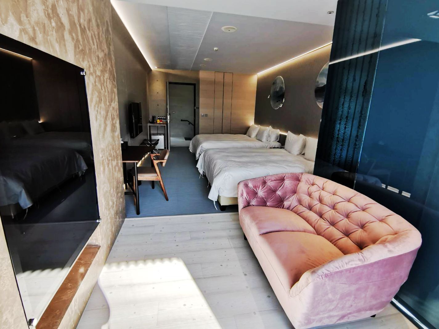 Une chambre d’hôtel moderne équipée d’un grand lit, d’un lit plus petit, d’un canapé, d’un bureau avec une chaise et d’une télévision.