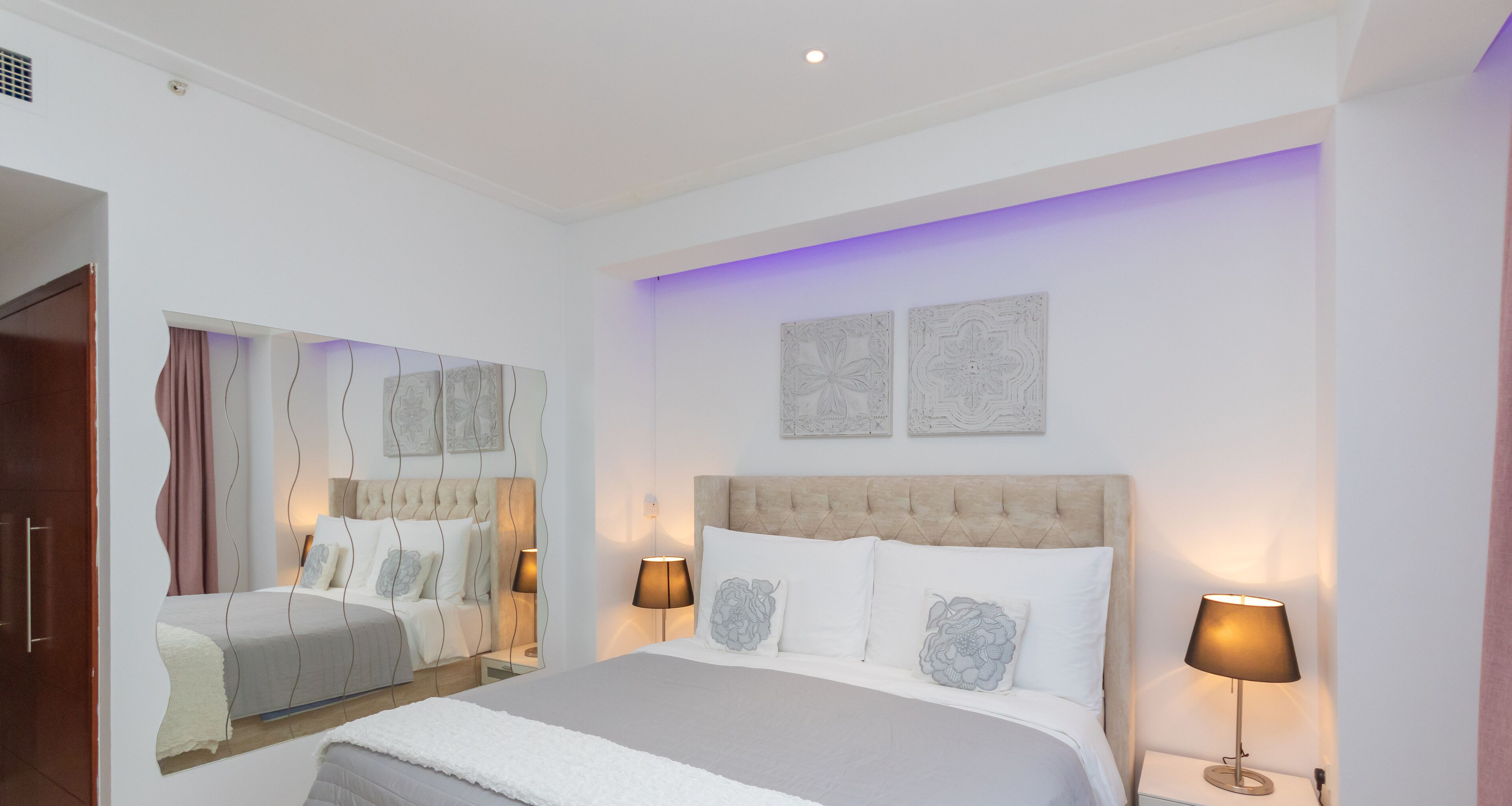 Une chambre moderne avec un grand lit, deux lampes de chevet et des œuvres d’art murales.