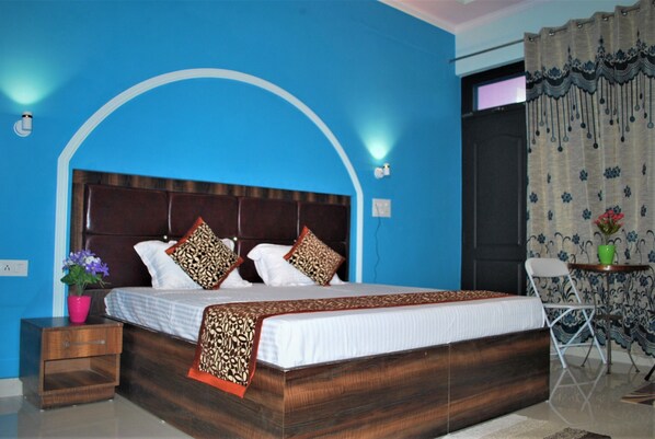 A bedroom with a large bed, a nightstand, a chair, and a small table with a vase.