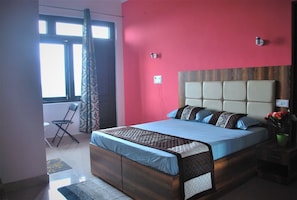 A bedroom with a bed, a chair, a window, and a nightstand.
