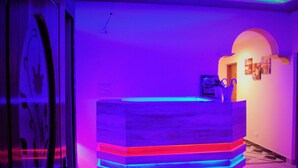 A reception desk with a modern design, a glass partition, and a wall-mounted artwork. - Billing Vista Guest House (Jogindarnagar)