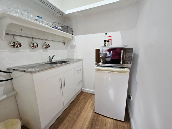 A compact kitchen with a sink, a microwave, and a small refrigerator.