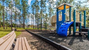 A playground with a slide and climbing structures, surrounded by a forested area. - Ffv8438ha - Highlands Reserve - 4 Bed 2.5 Baths Villa (Davenport)