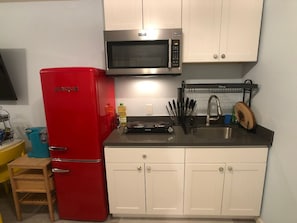 A compact kitchen with a red refrigerator, a microwave, and a sink.