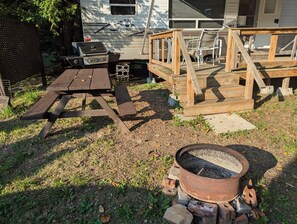 A campsite with a picnic table, grill, and a fire pit. - Springdale Trailer at Bon Echo Family Campground | Rustic Stay w/ Beach Access
 (Cloyne)