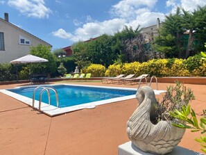En swimmingpool med liggestole og en dekorativ stent statue.