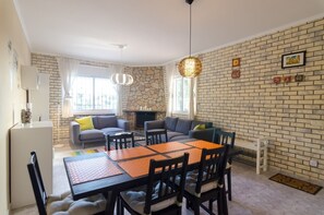 A modern living room with a fireplace, a dining table, and a stone accent wall.