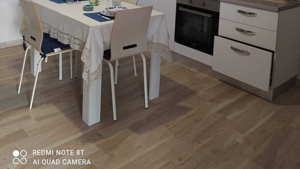 A modern kitchen with white cabinets, a gas stove, and a dining area with a table and chairs. - WONDERFUL CALALIBEROTTO (Sos Alinos)