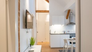 A modern kitchen with white cabinets, a built-in oven, and a dining area with a white table and chairs. - Meine Zeitwohnung (Essen)