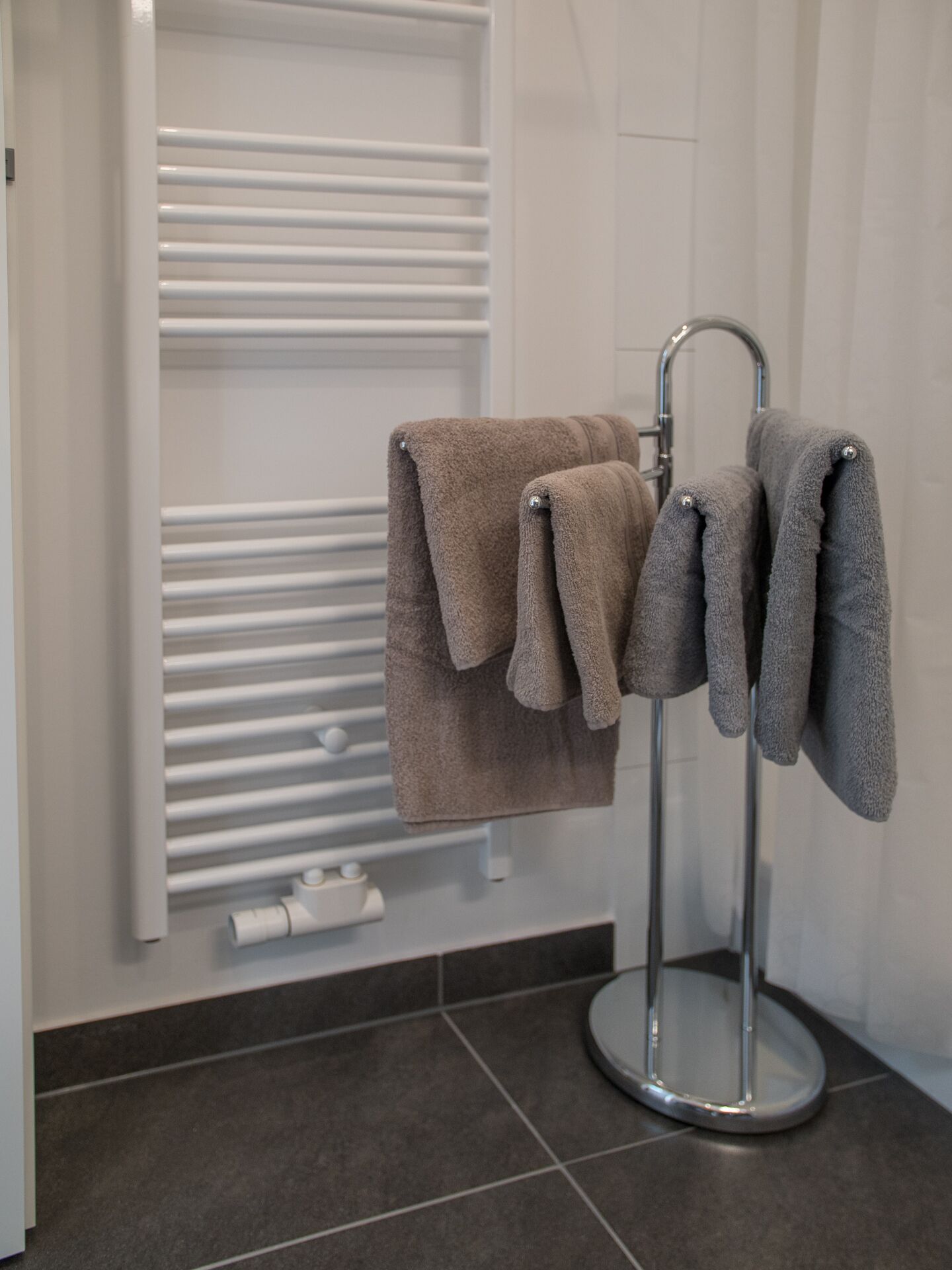Un bagno con un portasciugamani pieno di asciugamani, un termosifone bianco e un water.