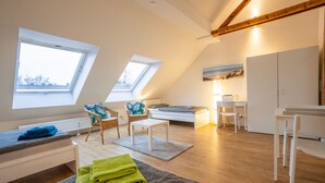 A modern loft bedroom with a sloped ceiling, skylights, a bed, a desk, and a wardrobe. - Meine Zeitwohnung (Essen)