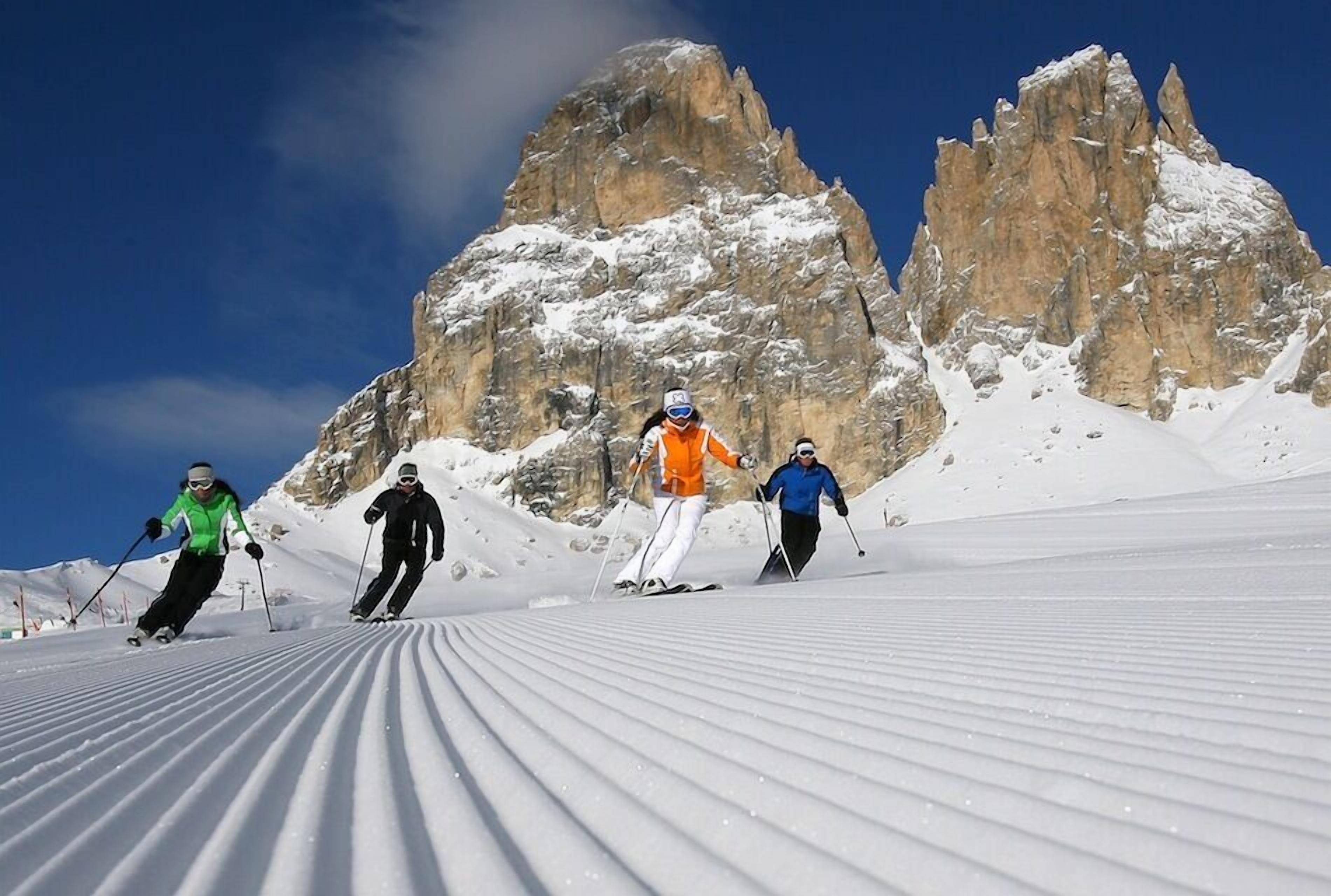Skiers on a snow-covered slope with a rocky mountain backdrop.