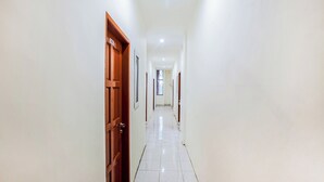 A long, narrow hallway with white walls and a tiled floor. - Hotel O Palem Mas Garden (Medan)