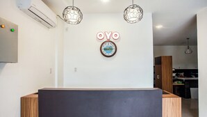A reception area with a wooden reception desk, a wall-mounted air conditioner, and two pendant lights. - Hotel O Palem Mas Garden (Medan)
