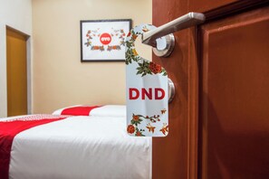 Een hotelkamer met een bed, een deur met een handgreep en een lijst met een afbeelding aan de muur.
