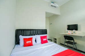 A hotel room with a bed, a desk, a chair, and a TV.