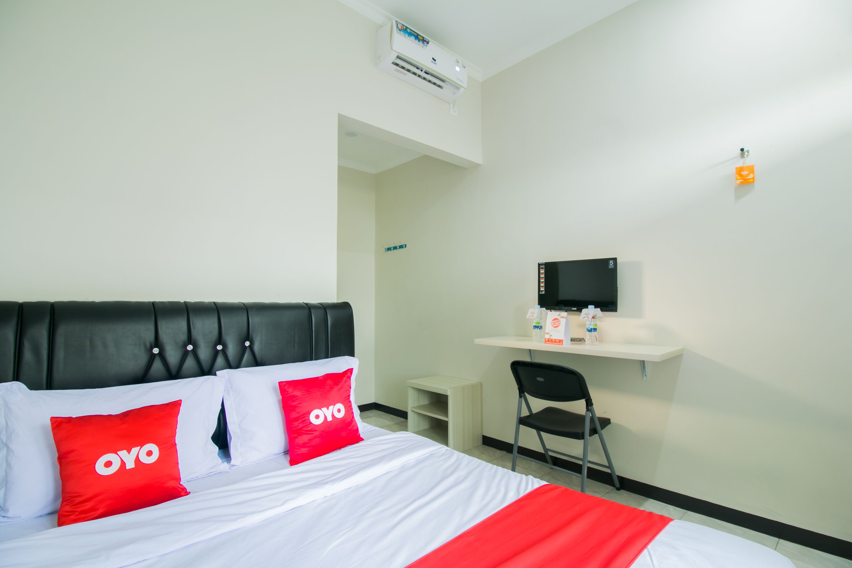 A hotel room with a bed, a desk, a chair, and a television.