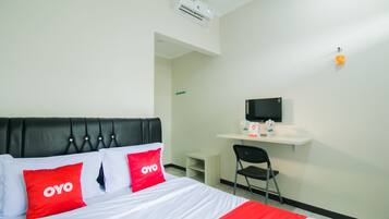 A hotel room with a bed, a desk, a chair, and a television.