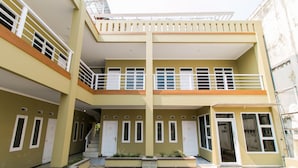 Un edificio de dos pisos con una escalera central, varias puertas y un balcón.