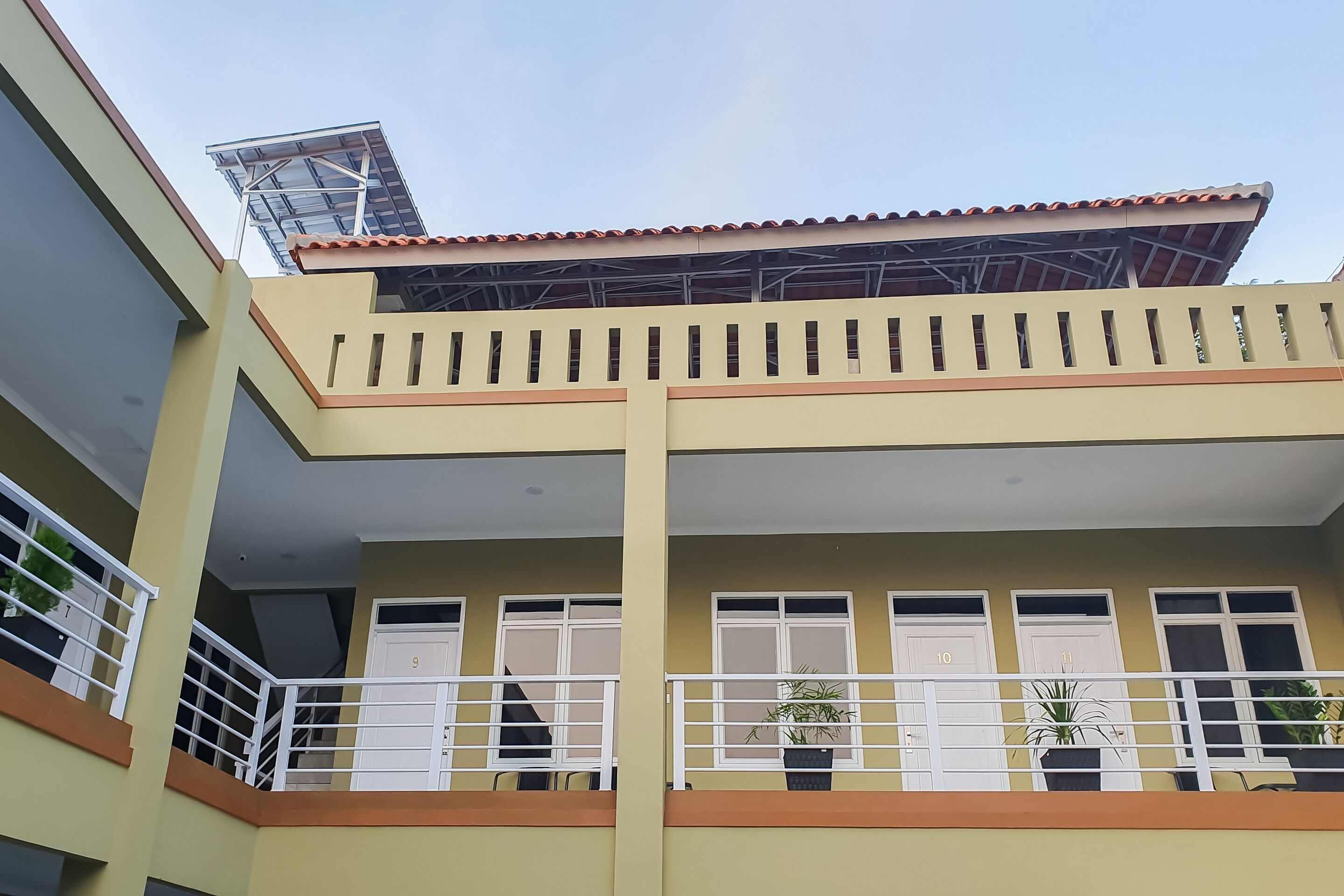 Un edifici de diverses plantes amb balcons, finestres numerades del 9 al 11 i plantes en testos als balcons.