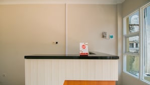 Un mostrador de recepción con encimera negra y base de madera, una pared blanca y una ventana con vistas a edificios.