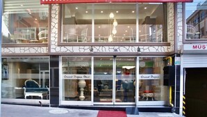 The exterior of the Grand Dogan Hotel with a prominent red sign, large glass windows, and a visible entrance.