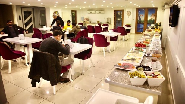 A dining area with tables and chairs, a buffet line with food, and a clock on the wall.