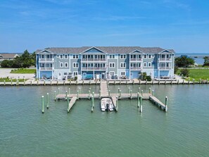 Een hotel aan het water met meerdere balkons, een steiger en een jachthaven.