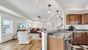 A spacious kitchen with a large island, wooden cabinets, and a checkered floor.