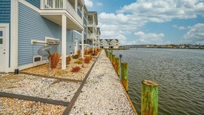 A waterfront hotel with a gravel walkway, wooden posts, and a view of the water.