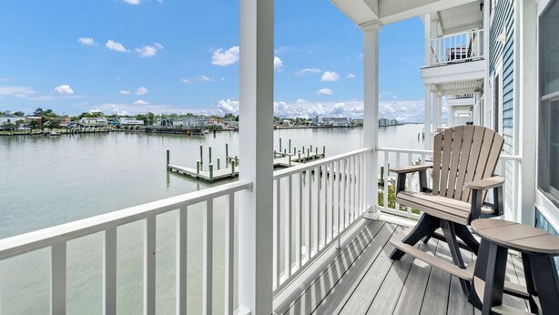 A wooden deck with a view of a calm body of water and distant buildings.