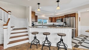 A modern kitchen with a central island, stainless steel appliances, and a checkered floor.