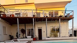 A two-story building with a swimming pool, outdoor seating, and a balcony with potted plants. - Family Choice with Pool View (Seixal)