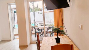 A dining area with a wooden table and chairs, a potted plant, and a TV mounted on the wall. - Family Choice with Pool View (Seixal)